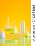 Small photo of Minimal concept with laboratory glassware - erlenmeyer flasks, boiling flasks and test tube filled with color liquid decorated on yellow background. An empty platform in the middle to display products