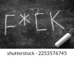 Small photo of obscene word written in chalk on a black background