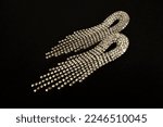 Small photo of Long dangling rhinestone earrings, on a black paper background