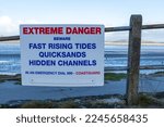 Small photo of ARNSIDE, ENGLAND - DECEMBER 2022. A sign warns of extreme danger from fast rising tides, quicksand, and hidden channels on Morecambe Bay.