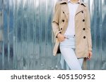 Slim girl in jeans, a beige coat and white shirt outdoors in spring, copy space.