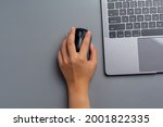 woman works with a laptop at home and holds a computer mouse in her left hand.