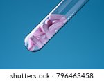 Laboratory glass test tube filled with pink pills on blue backround. Medicine research concept.