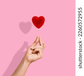 Small photo of Trendy composition made of Korean love sign, Finger Snapping on pink background. Minimal concept of Valentine's Day or love. Korea finger heart. Creative art, minimal aesthetics.