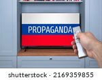 Small photo of Propaganda TV channels on Russian television. Agitation and russian propaganda in modern television. Misinformation citizen. Remote control in the hand of the guy watching russian news on TV. False TV