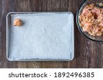 Turkey meatball mixture in a glass bowl, raw meatball on a parchment paper lined baking tray
