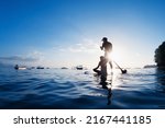 Small photo of Young happy couple have fun on stand up paddleboard. Active paddle boarder paddling by sunset sea. Healthy lifestyle. Water sport, SUP surfing tour in adventure camp on family summer beach vacation