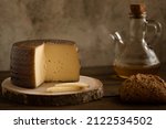 Small photo of Manchego cheese board on wooden board with nuts, bread and oil on a dark rustic background.