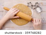 Rolling out dough for gingerbread. Pastry hands, rolling pin, dough, parchment, molds in the shape of the star, the flour in a sieve. The process of making gingerbread cookies at home. Top view.