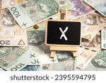 a small wooden writing board standing on scattered Polish zloty PLN banknotes, a chalk inscription 