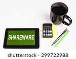 Small photo of Business Term / Business Phrase on Tablet PC - Cup of coffee, Pens, Calculator and a green/yellow note pad on a White surface - White Word(s) on a green background - Shareware
