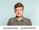 Small photo of awkward gawky fumbling oafish dorky man facial expression. portrait of a young guy on light background. emotion facial expression. feelings and people reaction.