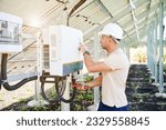 Small photo of Professional worker checking voltage on solar inverter. Male using current probe to measure output voltage. Man in helmet pointing at inveter dial on back side of PV panel.