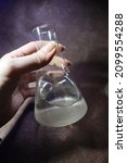 Small photo of Photo of a flask with acid held by a girl. Flask with nitric, phosphoric, sulfuric acid, hydrochloric acid