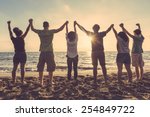 Multiracial group of people with raised arms looking at sunset. Backlight shot. Happiness, success, friendship and community concepts.