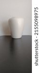 Small photo of Vase: unadorned on black table against white wall.