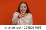 Small photo of Amused pretty woman pointing finger to camera, laughing out loud, taunting making fun of ridiculous appearance, funny joke anecdote, bullying. Young adult girl isolated alone on red studio background