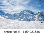 Ski slope, Peak Ine and Mt. Sofrudzhu in winter sunny day. Dombay ski resort, Western Caucasus, Russia.
