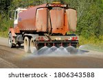 Small photo of Water Truck Spraying Gravel Road to Suppress Dust and Prepare for Asphalting