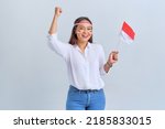 Small photo of Excited young Asian woman celebrate Indonesian independence day holding the Indonesian flag isolated on white background
