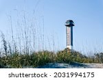Small photo of Sullivan's Island Lighthouse. Clear daytime weather. Beach dunes and grass in foreground.