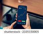 Businessman trader using smartphone with stock market investments and graph on screen to analyze trading data, buy or sell and checking price on mobile application.