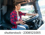 Small photo of A young beautiful woman sits in the cab of a cargo truck and drives a cross-country tour