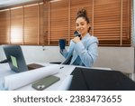 Small photo of In a contemporary office space, a curly-haired businesswoman adeptly uses her laptop to manage tasks and ensure efficiency, combining style and functionality.