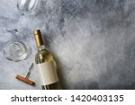 Unopened vintage bottle of white wine with blank label, empty wineglass & bunches of different grapes on wooden table background. Expensive bottle of chardonnay concept. Copy space, top view, flat lay