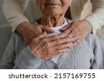 Unrecognizable female expressing care towards an elderly lady, hugging her from behind holding hands. Two adult women of different age. Family values concept. lose up, copy space, background.