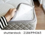 Small photo of Cropped shot of man showcasing the waterproof topper for white orthopedic mattress. Male unzipping hypoallergenic foam matress protector. Close up, copy space, top view, background.
