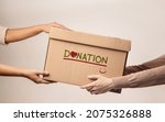 Small photo of Donation Concept. The Volunteer Giving a Donate Box to the Recipient. Standing against the Walll