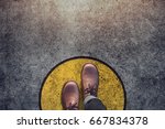 Comfort Zone concept, Male with leather shoes steps over circle line to outside bound, Top view and Dark tone, Grunge Dirty Concrete Floor as Background