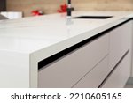 Modern white lacquer and ash tree wood kitchen cabinet equipment and black faucet on white granite countertop