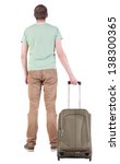 Small photo of Back view of man with green suitcase looking up. Rear view people collection. backside view of person. Isolated over white background. man in a T-shirt holding a duffel bag on wheels