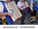 Small photo of Chichester, Sussex, UK - 20 Apr 2019: Accordion players from the Sussex Martlet Sword and Morris dancers, in blue and yellow tunics, play a traditional folk dance in the street. Very shallow focus.