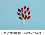 Small photo of Women's and gynecological health care. Menstrual cycle. Hygiene care during critical days. Tampon woman Clean lie on a blue background among red petals, safe Menstruation, means of protection.