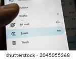 Small photo of A human finger in the gloom, pressing a spam button in a mail program, on a blurred background of a smartphone screen. Fight spam and advertising marketing campaigns.