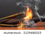 Small photo of The wiring is burning and sparking on a dark background. A short circuit in the twisted wires from the computer. Flames, sparks and smoke.