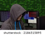 A hacker sits behind computer monitors on an abstract background, attacking and hacking servers with a virus. Creation and dissemination of disinformation, DDOS attack