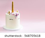 Cute unicorn layered cake decorated with meringues. Pink background.