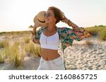 Small photo of pretty attractive slim smiling woman on sunny beach in summer style fashion trend outfit happy, freedom, wearing white top, jeans and colorful printed tunic boho style chic and straw hat