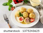 Cottage cheese dumplings with fresh strawberry, served with sour-honey sauce, delicious summer dessert on a bright stone table. 