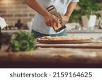 A woman uses a grater while making homemade pizza with cheese