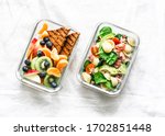 Office sweet and savory food lunch box. Pasta, tuna, spinach, avocado salad and fruit, peanut butter sandwiches lunch box on light background top view       