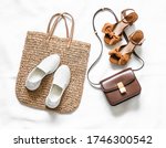 Variety of women's shoes and bags - straw shopper bag and sneakers and  elegant leather cross body bag and suede sandals on a light background, top view     