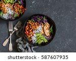 Grilled chicken, rice, spicy chickpeas, avocado, cabbage, pepper buddha bowl on dark background, top view. Delicious balanced food concept    