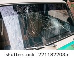 
Close up of a broken windshield of an old car. The glass pane has two impacts and cracks. Maybe after a riot, accident or demonstration in the city