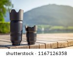 Zoom lens and lens with fixed focal length from digital camera standing on wooden board with mountain landscape at background