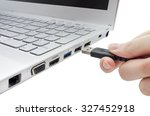 Hand inserting black USB cable into laptop isolated on white background